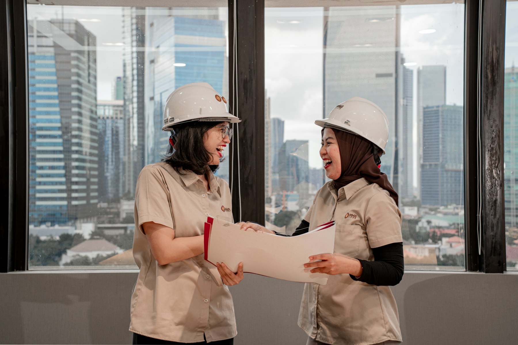 Two engineers in hard hats reviewing drawings in a city office